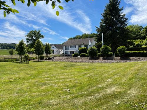 a house with a large lawn in front of it at Ferienanlage Villa Maare in Gillenfeld