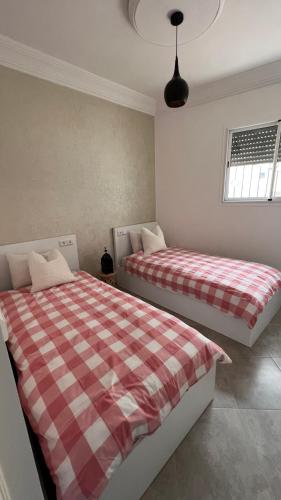 a bedroom with two beds and a window at Tiwaline Tarsime App B in Sidi Ifni
