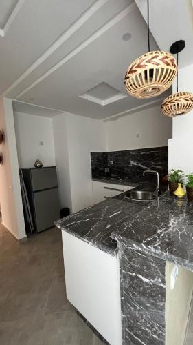 a kitchen with a black counter top and a sink at Tiwaline Tarsime App B in Sidi Ifni