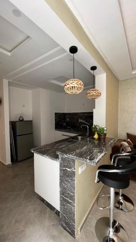 a kitchen with a counter with a sink and chairs at Tiwaline Tarsime App B in Sidi Ifni