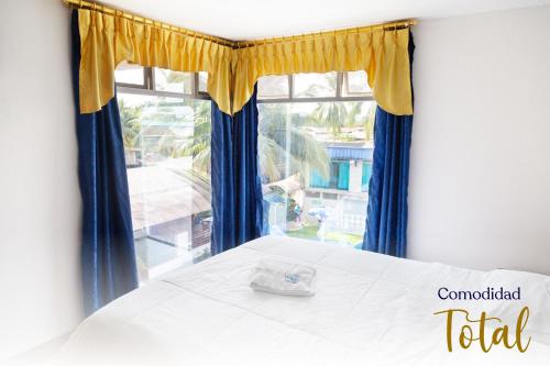 1 dormitorio con 1 cama con cortinas azules y amarillas en Hotel La Cascada - Lago Agrio, en Nueva Loja