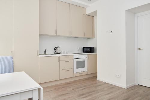 a white kitchen with white cabinets and a table at New apartment next to Cathedral Square in Vilnius