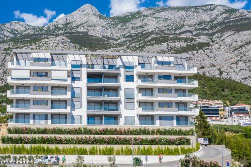 a white building with mountains in the background at Luxury apartment EL Paradiso Sea & City view in Makarska
