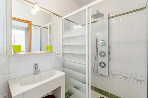 La salle de bains blanche est pourvue d'un lavabo et d'une douche. dans l'établissement Villa Côté Sud, à Marseille