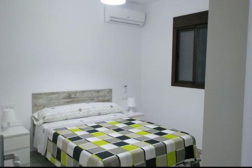 a bedroom with a bed with a checkered blanket at Villa la Parra in Chiclana de la Frontera