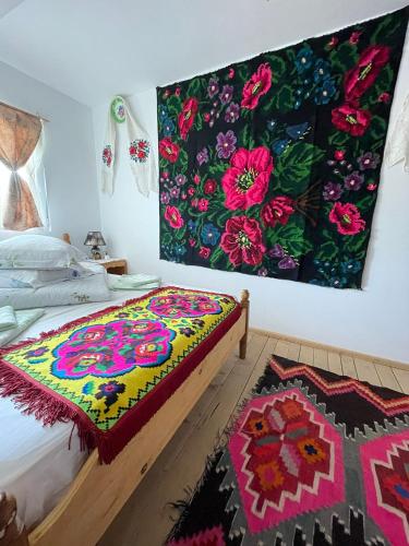 a bedroom with a bed with a colorful blanket on the wall at Casa Pintea de Sub Coastă in Breb