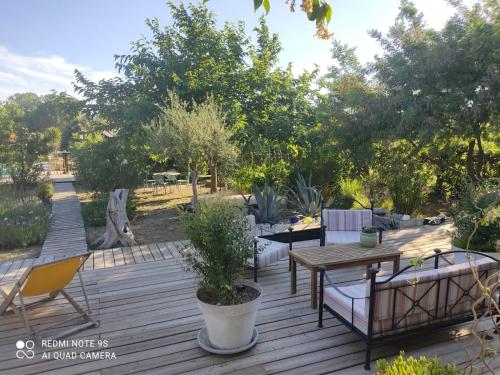 a wooden deck with a table and chairs and trees at B&B La Terre Brûlée in Aigues-Mortes
