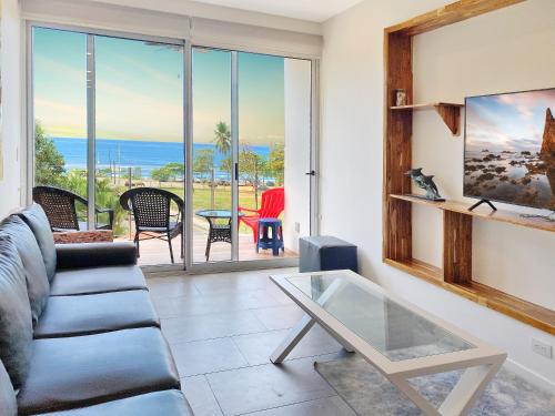 ein Wohnzimmer mit Sofa und Glastisch in der Unterkunft SUNSET OCEAN VIEW CONDO in Jacó
