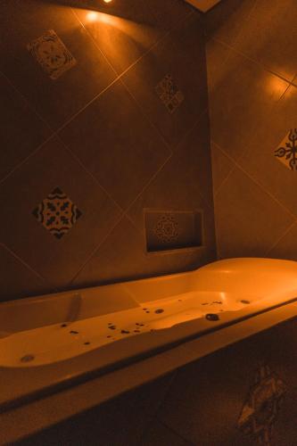 a bathroom with a bath tub with lights on the wall at Pousada Adega Cipo in Serra do Cipo