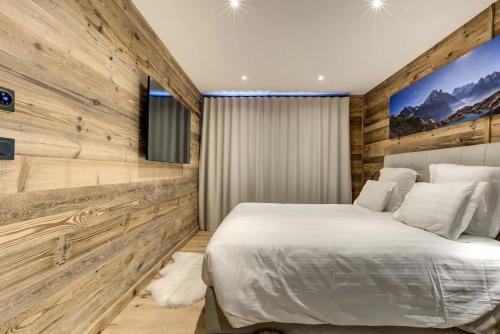 Amazing chalet في شامونيه مون بلان: غرفة نوم بسرير ابيض وجدران خشبية