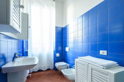 baño de azulejos azules con lavabo y aseo en Residenza di Prestigio In Riva al Lago Marone Primo Piano, en Marone