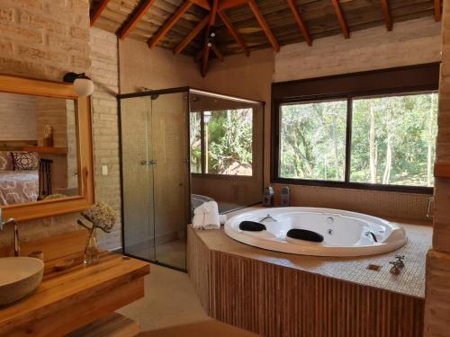 uma grande casa de banho com banheira e chuveiro em Pousada Toca Da Coruja em Monte Verde