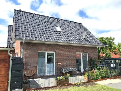 a red brick house with a black roof at Feriendomizil Dornum Haus Margarete mit Wallbox in Dornum