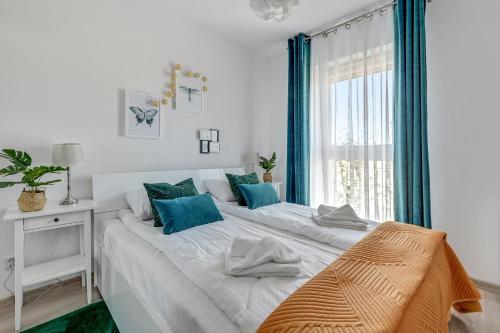 a white bedroom with a large bed with blue accents at Wave Apartments - Cztery Oceany 2 in Gdańsk