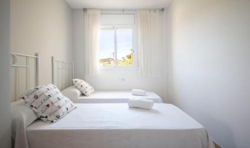 a white room with a bed and a window at R129 Apartamento con terraza y piscina comunitaria cerca de la playa in Calafell