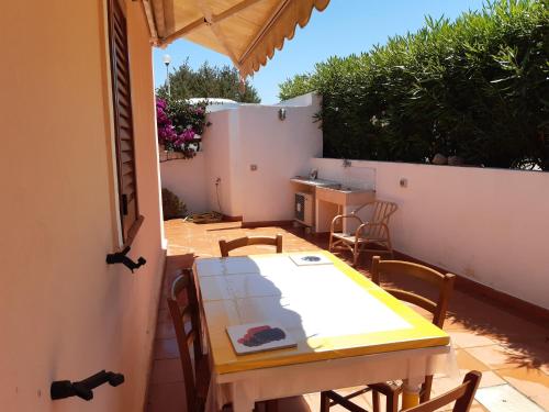 a patio with a table and chairs and a kitchen at Mare & Mirice - Case Appartamenti Vacanza in Aglientu