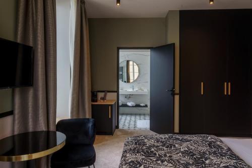 a bedroom with a bed and a chair and a mirror at Hotel de la Plage in Lion-sur-Mer