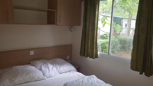 een bed in een slaapkamer naast een raam bij SunVillage Camp- Mobilházak Alsóörsön in Alsóörs