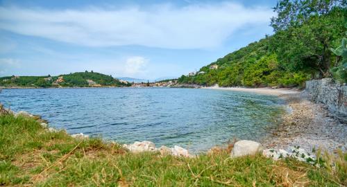 a body of water with a beach and trees at Villa Spiros Imerolia Kassiopi in Kassiopi