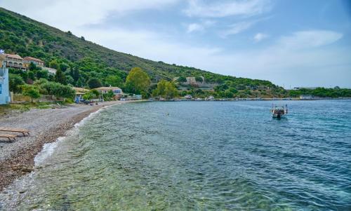 a boat in the water next to a beach at Villa Spiros Imerolia Kassiopi in Kassiopi