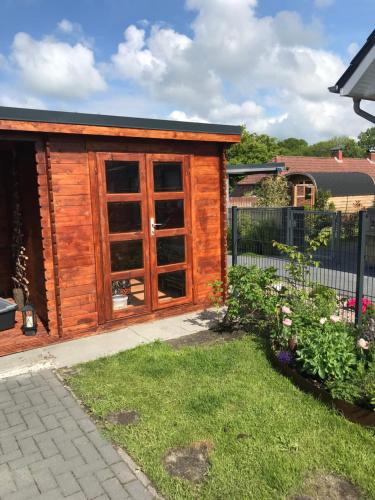 a wooden shed with a large wooden door at Feriendomizil Dornum Haus Margarete mit Wallbox in Dornum