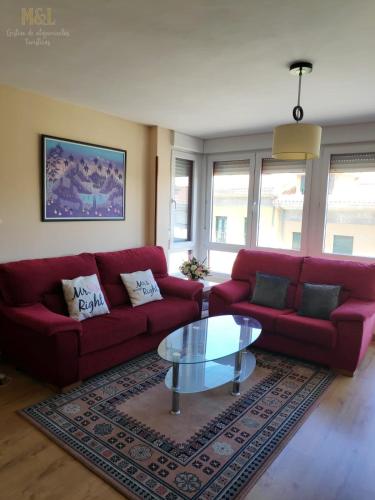 a living room with a red couch and a glass table at El trocito de mar in Luanco