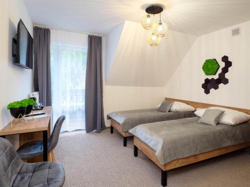 a bedroom with two beds and a table and a chair at Osada turystyczna Malinów in Szczawnica