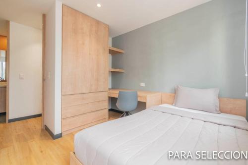 a bedroom with a white bed and a desk at CentralX 21 Bogotá in Bogotá