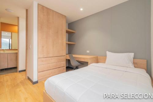 a bedroom with a white bed and a desk at CentralX 21 Bogotá in Bogotá