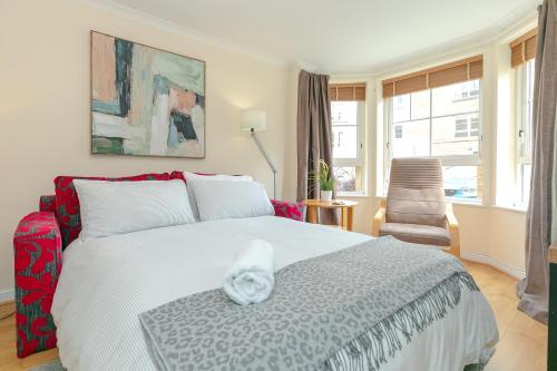 1 dormitorio con 1 cama blanca y 1 silla en Dicksonfield Quiet Central Family Apartment with Parking, en Edimburgo