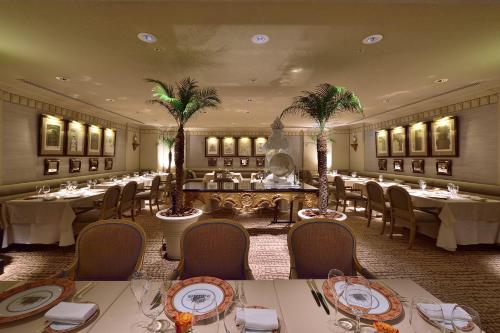 a dining room with tables and chairs and palm trees at Hotel Nikko Fukuoka in Fukuoka