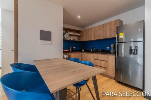 a kitchen with a wooden table and blue chairs at CentralX 21 Bogotá in Bogotá