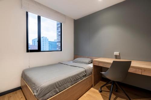 a bedroom with a bed and a desk and a window at CentralX 21 Bogotá in Bogotá