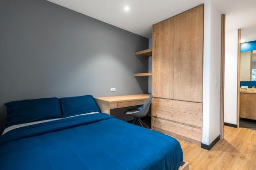 a bedroom with a blue bed and a desk at CentralX 21 Bogotá in Bogotá