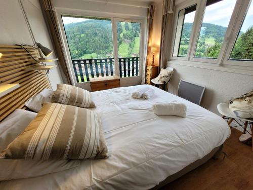 un grand lit dans une chambre avec une grande fenêtre dans l'établissement Appartement skis aux pieds avec piscine, rénové et confortable - FR-1-598-18, aux Gets