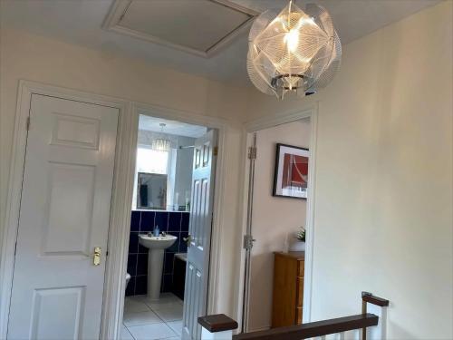 a hallway with a white door and a chandelier at Exclusive Homely Cambridge 4 bed house with free parking, big garden and sleeps 10 in Cambridge