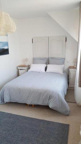 - une chambre dotée d'un lit blanc avec des draps et des oreillers blancs dans l'établissement Maison de vacances 3* à 50m de la plage, à Tréffiagat