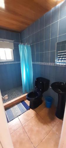 a bathroom with a black toilet and a blue tiled wall at Tu casa de playa, Menus del Mar, te espera pronto in San Carlos