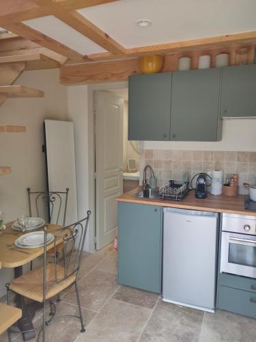 une cuisine avec des armoires blanches et une table et une salle à manger dans l'établissement Le Secret du Moulin, agréable tiny house Villefort, à Villefort