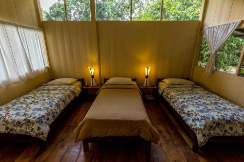 2 Betten in einem Zimmer mit 2 Fenstern in der Unterkunft Anaconda Lodge Ecuador in Ahuano
