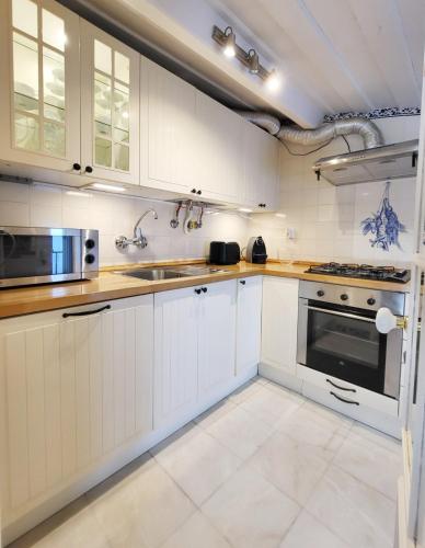 a white kitchen with white cabinets and a sink at Lisbon Cottage Principe Real in Lisbon