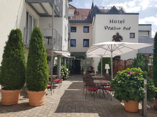 an outdoor patio with tables and chairs and an umbrella at Hotel-Restaurant Pfälzer Hof in Edenkoben