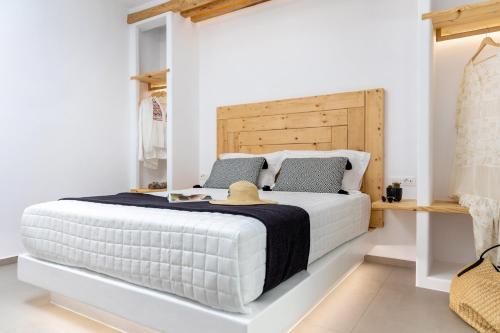 a bedroom with a white bed with a wooden headboard at Alenor City Hotel in Naxos Chora
