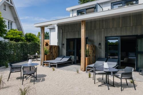 a patio with tables and chairs next to a building at Boutique Hotel Helder I Kloeg Collection in Renesse