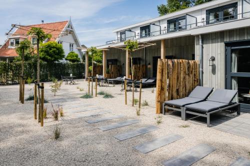 a patio with chairs and trees in front of a building at Boutique Hotel Helder I Kloeg Collection in Renesse
