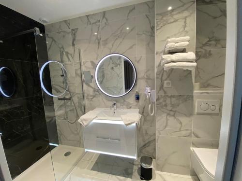 a bathroom with a sink and a shower with a mirror at Hotel Restaurant Lesage in Sarzeau