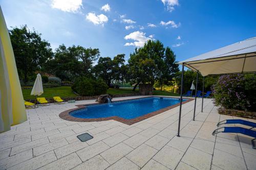 a swimming pool with an umbrella on a patio at Apartamentos Rurais - Casas do Lagar in Rosmaninhal