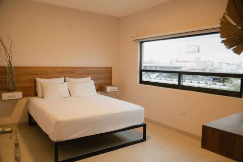 a bedroom with a bed and a large window at Hotel Fratelli in Aguascalientes