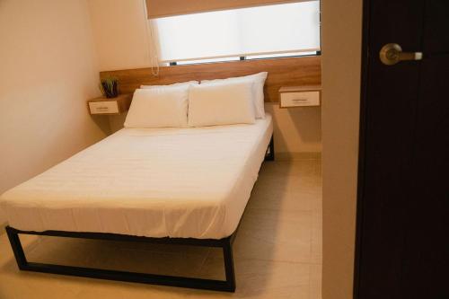 a bed in a small room with a window at Hotel Fratelli in Aguascalientes