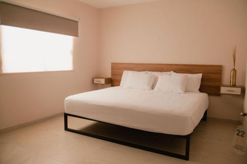 a bedroom with a large white bed with a window at Hotel Fratelli in Aguascalientes